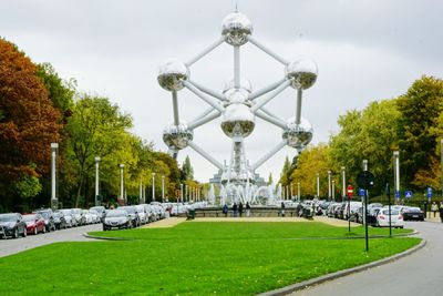 Atomium by fountain against cloudy sky