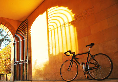 Low angle view of bicycle against wall on sunny day