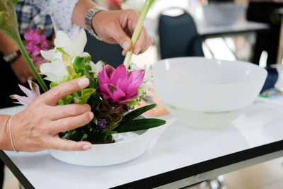 Midsection of woman holding flower at shop