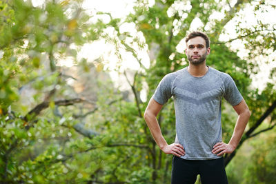 Portrait of young man standing against trees