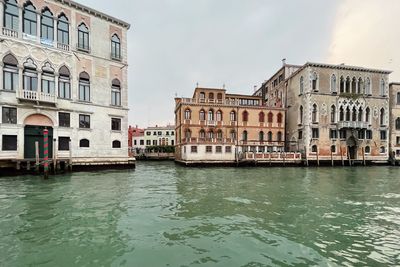 Buildings by river against sky