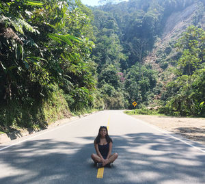 Portrait of smiling young woman sitting on road