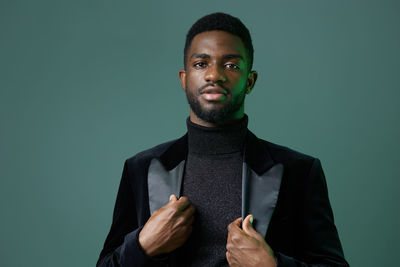 Portrait of young man standing against black background