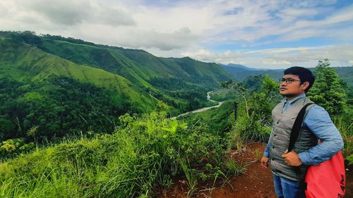 Young man standing on mountain against sky