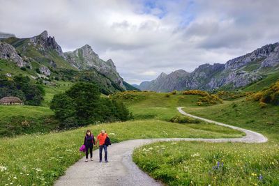 People walking on road against mountain range