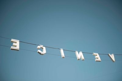 Low angle view of venice text on cable against blue sky