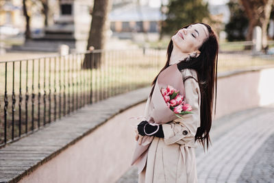 Spring, self love, self care. candid portrait of happy woman with tulips bouquet outdoors