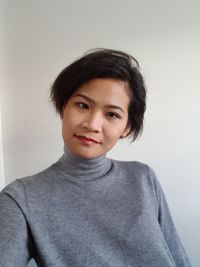 Portrait of smiling young woman against wall at home