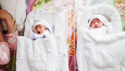 High angle view of cute twins sleeping on bed at home