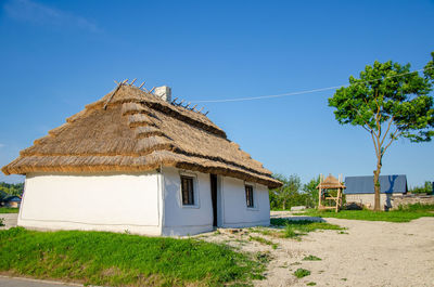 Rural landscape with ancient ukrainian clay house. thatched roof, white walls with lime, chimney.