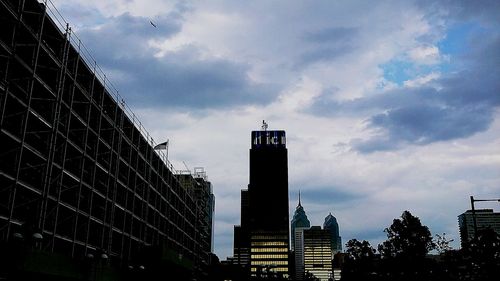 Low angle view of modern buildings against cloudy sky