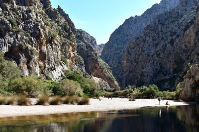 Scenic view of river by mountains against clear sky