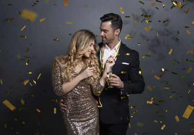 Couple standing amidst confetti against black background