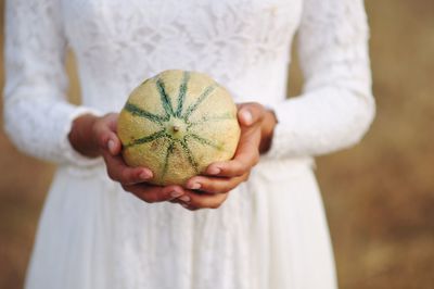 Midsection of bride holding melon outdoors