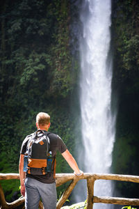 Rear view of man looking at waterfall