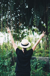 Rear view of woman standing by plants in forest