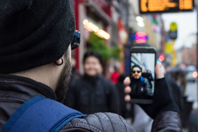 Rear view of woman photographing with mobile phone in city