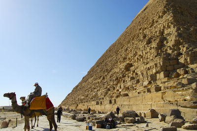 Low angle view of people sitting on desert against clear sky