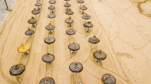 High angle view of thatched roofs at sandy beach