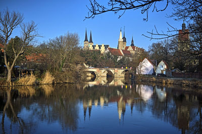 Arch bridge over river amidst buildings against sky