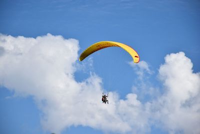 Low angle view of man paragliding against sky