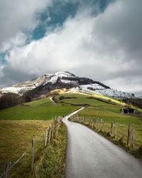 Road amidst green landscape against sky