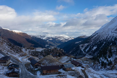 Snow covered houses by mountains against sky