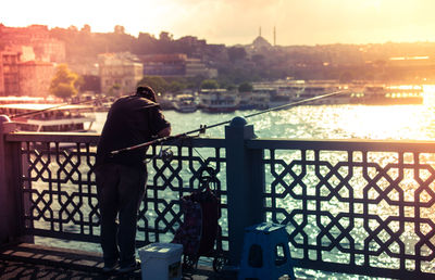 Rear view of man looking at cityscape against river