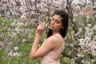 Low angle view of woman standing by pink flowering tree