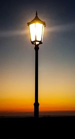 Low angle view of illuminated street light against sky at sunset