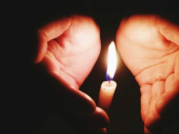 Close-up of human hand cupped by candle flame