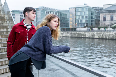 Couple standing by river in city