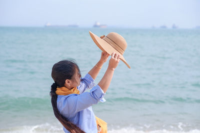 Rear view of man holding surfboard at beach