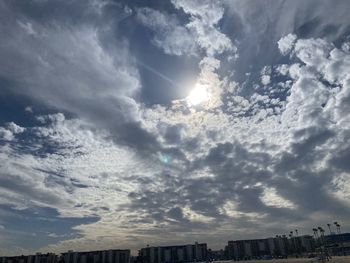 Low angle view of sunlight streaming through clouds in sky