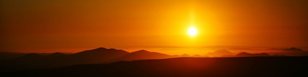 Scenic view of silhouette mountains during sunset