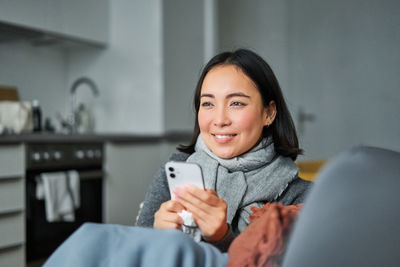 Portrait of young woman sitting on sofa at home