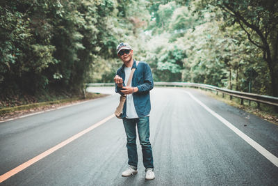 Full length portrait of young man standing on road