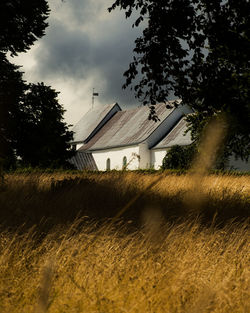 Houses on field by buildings against sky