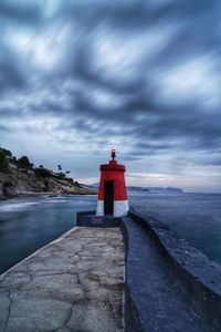 Lighthouse by sea against sky