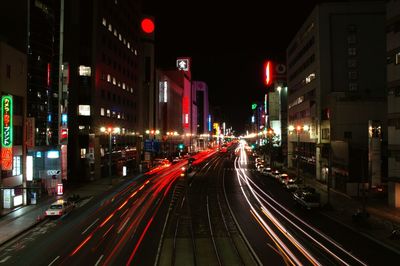 Light trails along buildings on urban street at night