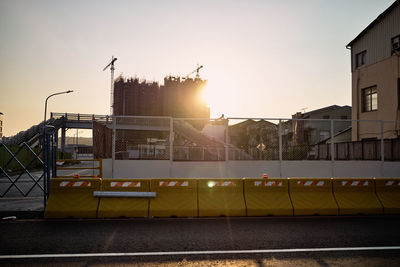 Street by buildings against sky during sunset