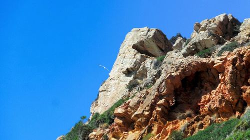 Low angle view of rock formation against clear blue sky