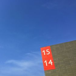 Low angle view of sign board against blue sky