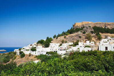 Scenic view of townscape by sea against clear blue sky