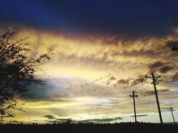 Low angle view of silhouette electricity pylon against sky during sunset