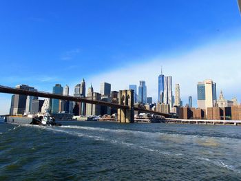 Sea by cityscape against blue sky