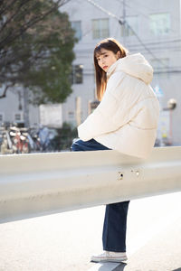 Portrait of young woman standing against wall