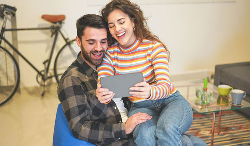 Cheerful woman taking selfie with boyfriend while sitting at home