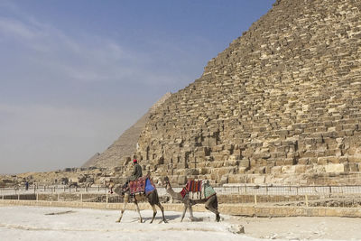 Man riding horse on desert against sky