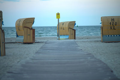Hooded chairs on beach against clear sky